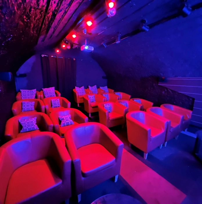 Tu fewn i sinema danddaearol. Mae seti cyfforddus gyda chlustog ar bob un.