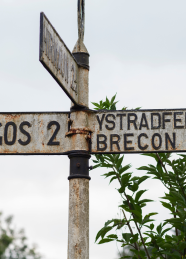 Arwydd ffordd yn dangos yr enwau Rhigos, Brecon ac Ystradfellte