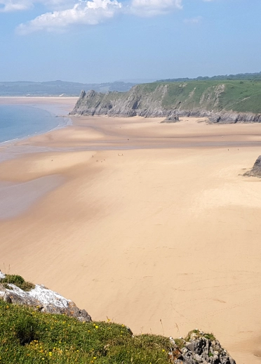 Traeth tywodlyd helaeth gydag ymyl o chlogwyni uchel