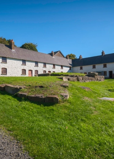 Rhes o adeiladau gwyn ar ben ardal laswellt