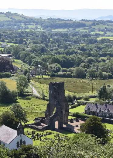 Golygfa ar draws cwm gydag abaty’n amlwg yn y blaendir.