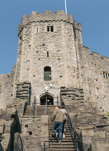 Gorthwr castell gyda dau o bobl yn cerdded i fyny’r grisiau