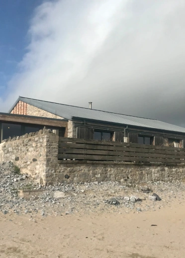 Bwyty pren ar draeth gyda theras allanol.