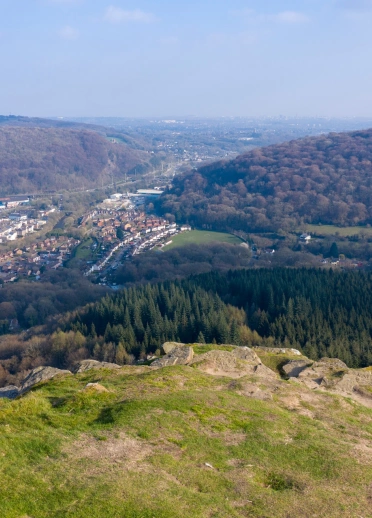 Golygfa o ben mynydd gyda choed a tai