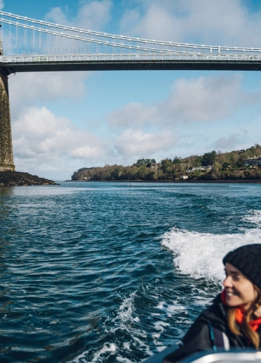 woman on rib boat and bridge in background.