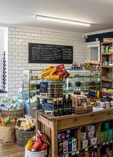 Inside Y Groser Harlech deli, with shelves of local produce and a central deli counter.