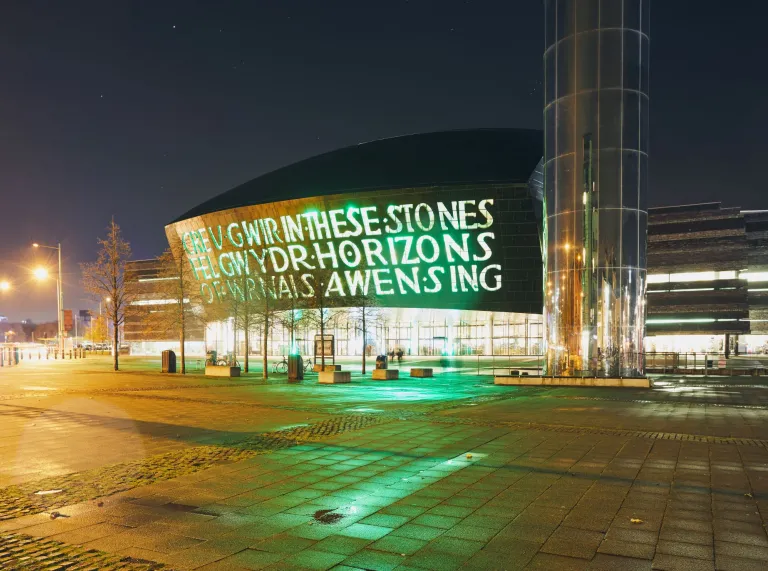 Exterior of Wales Millennium Centre and the water tower on Roald Dahl pass at night.