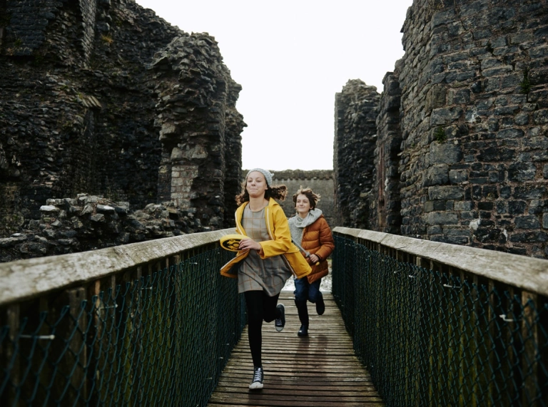 Dau blentyn yn rhedeg ar draws pompren yn syth at y camera