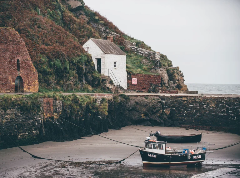 Cwch bysgota a thŷ bach gwyn ym Mhorthgain