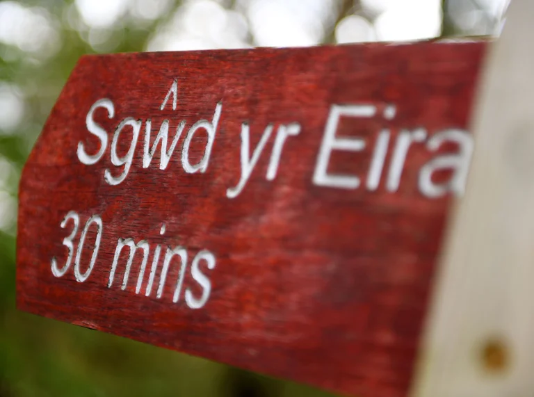 Arwyddbost pren coch a gwyn yn dweud ‘Sgwd yr Eira 30 munud’.