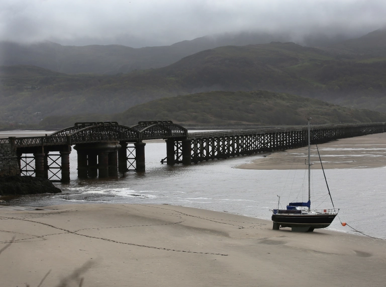 Pont rheilffordd a chwch bychan adeg llanw isel