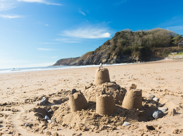 Cestyll tywod ar y traeth gyda'r môr a'r awyr yn y pellter.