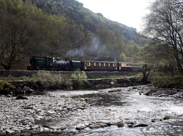 trên yn teithio ar hyd y traciau heibio afon yn llifo