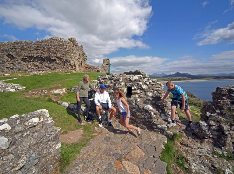 Dau oedolyn a dau o blant yn archwilio Castell Cricieth.
