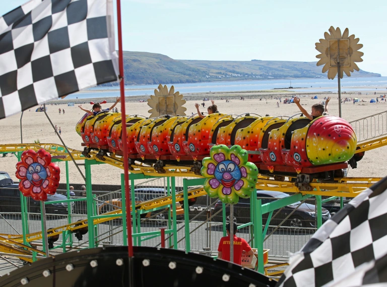 Taith ffair gyda thraeth tywodlyd yn y cefndir.