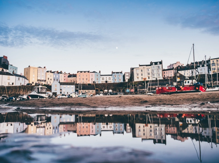 Harbwr Dinbych-y-pysgod gyda'r tai lliwgar yn adlewyrchu yn y môr