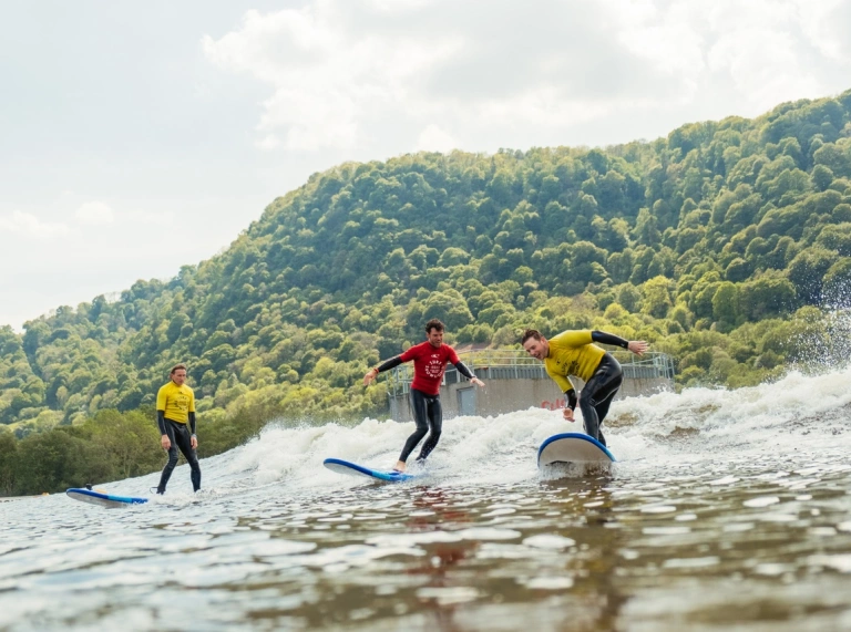 Tri pherson ar fyrddau syrffio yn Adventure Parc Snowdonia