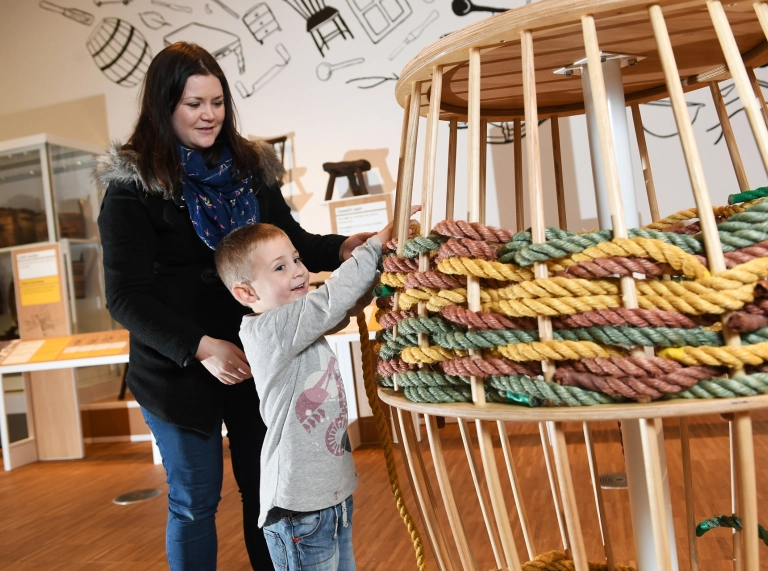 Menyw a phlentyn yn edrych ar fasged fawr a wehyddwyd