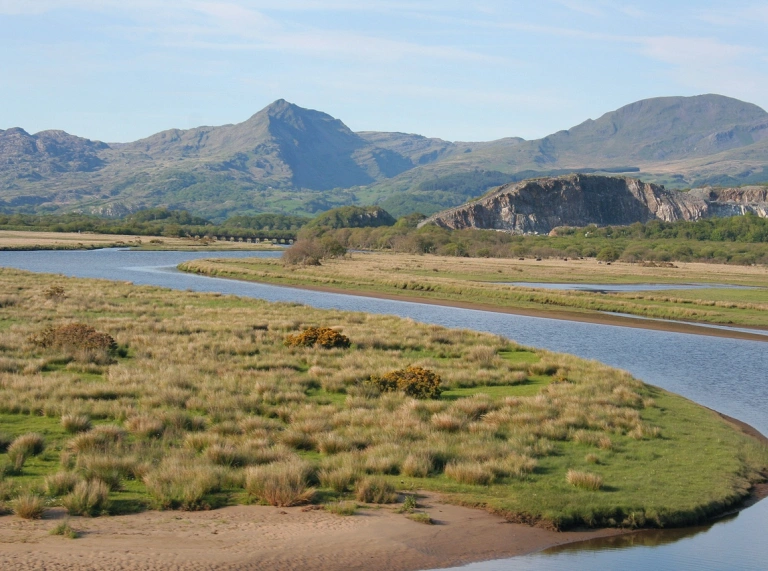 Traeth gyda mynyddoedd mawr yn y cefndir