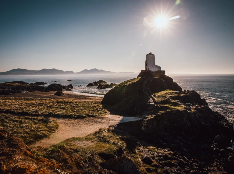 Goleudy Llanddwyn a'r traeth yn haul cryf y gaeaf