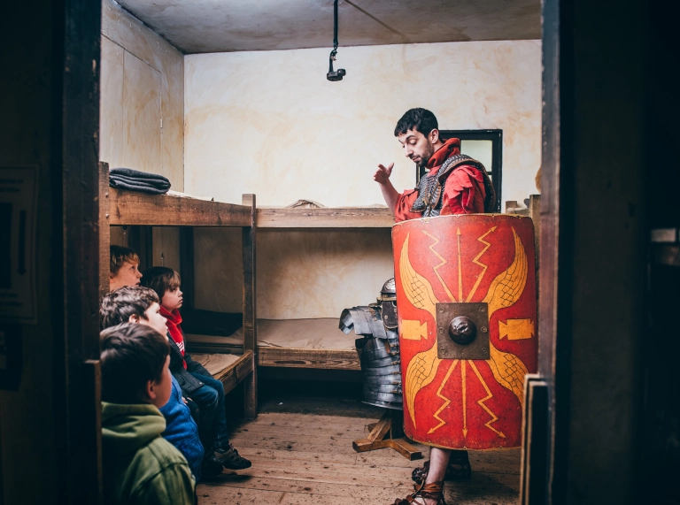 A man dressed as a Roman soldier talking to children.