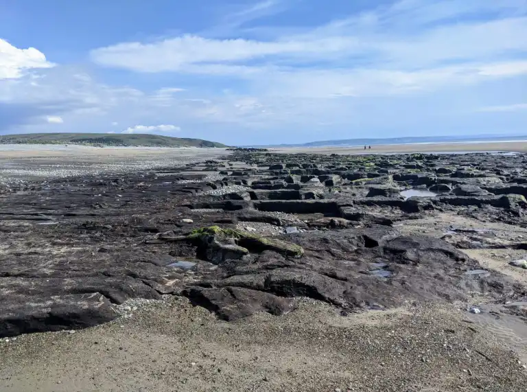 Traeth gyda cherrig sgwar ac awyr las.