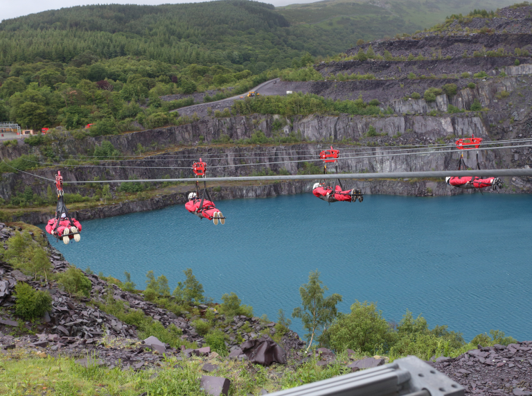 Pedwar person ar Zip World Velocity uwchben llyn Chwarel y Penrhyn.