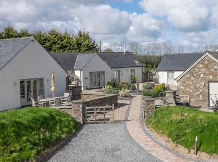 Y tu allan i grŵp o fyngalos gwyliau wedi'u paentio'n wyn.