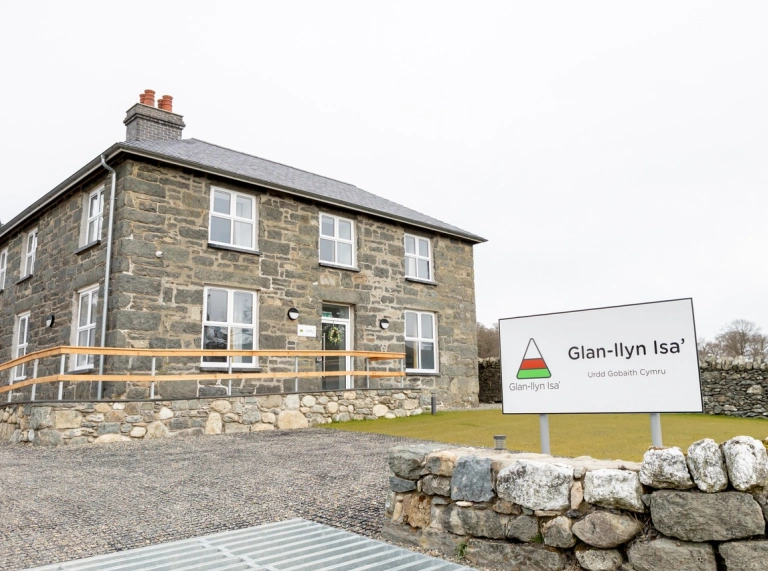 A large stone house with the Glan-llyn Isa’ sign outside.