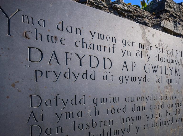 Bedd lechen Dafydd Ap Gwilym gydag ysgrifen wedi'i cherfio ynddi