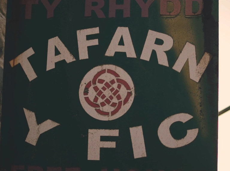 Arwydd Tafarn y Fic. Mae'r arwydd yn ddu, yr ysgrifen yn wyn ac mae cwlwm Celtaidd coch a gwyn yn y canol.