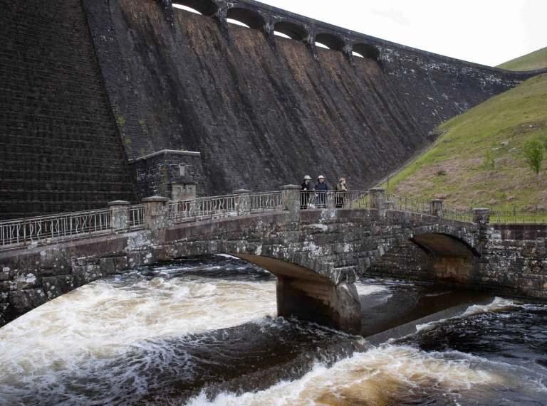 Pont gerrig gyda phobl arni, o dan argae.