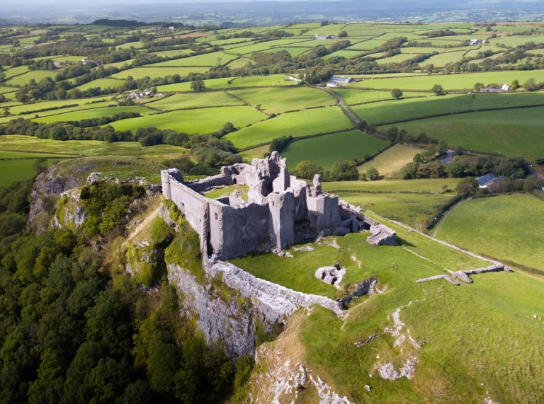 Llun o'r awyr o gastell ar fryn yng nghanol caeau gwyrdd.