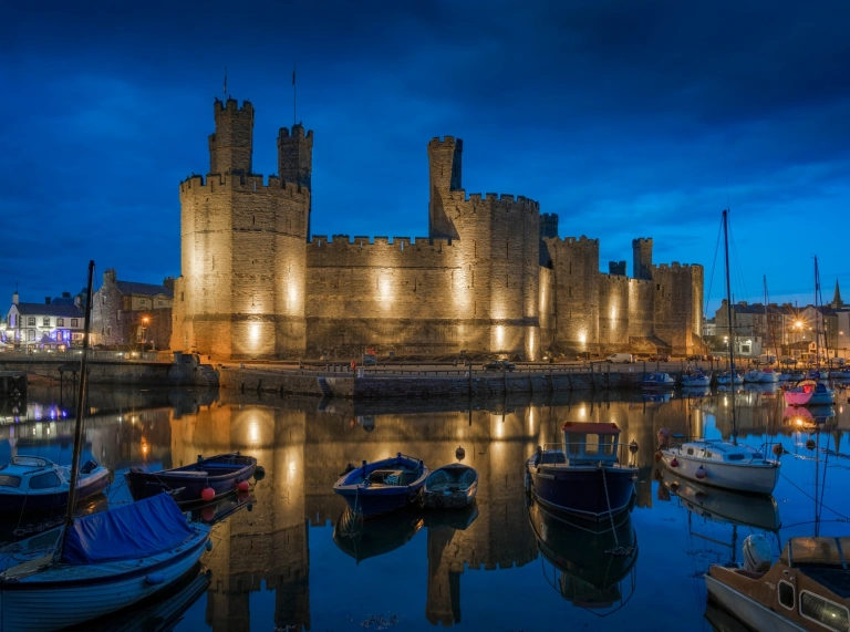 castle at night viewed from water.