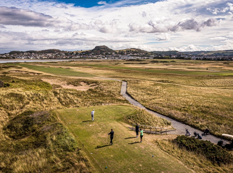 Pobl yn chwarae golff ar gwrs golff arfordirol.