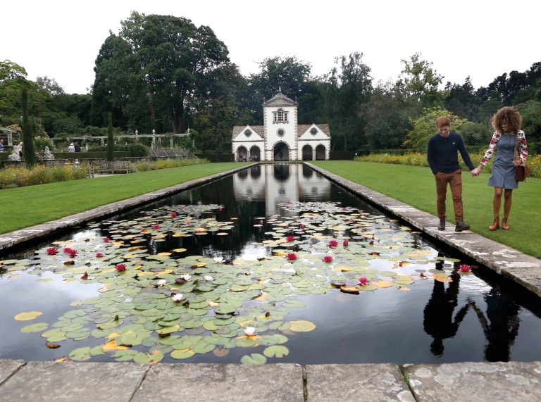 lily pond and couple walking besides it.