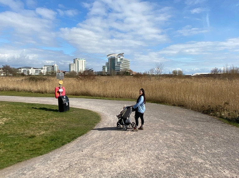 Menyw yn cerdded gyda phram ym Mae Caerdydd