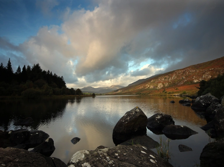 Golygfa o lyn gyda mynydd a choed o gwmpas