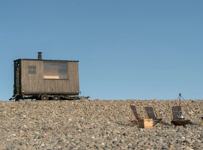 sauna and pebbly beach with deck chairs.