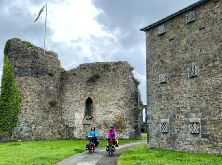 Dau berson yn seiclo heibio castell