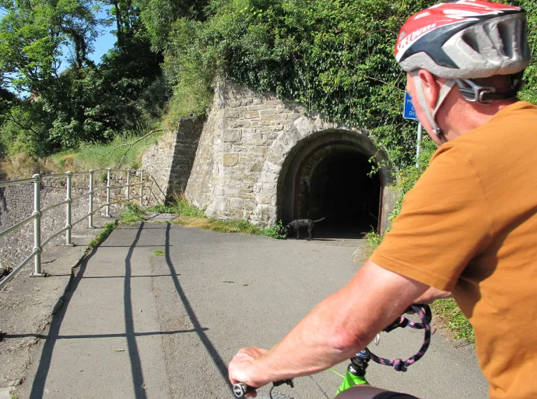 Beiciwr yn gwisgo helmed ar lwybr ger twnnel.