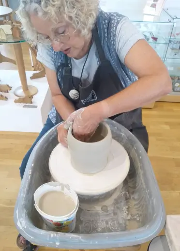 Dynes wrth droell crochenydd yn gwneud pot
