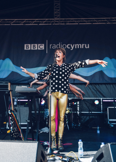 Llun o Tara Bethan o'r grŵp Lleden yn perfformio ar lwyfan Tafwyl yn gwisgo trowsus aur