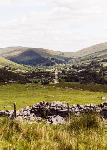 Golygfa o gaeau a mynyddoedd o amgylch pentref bach