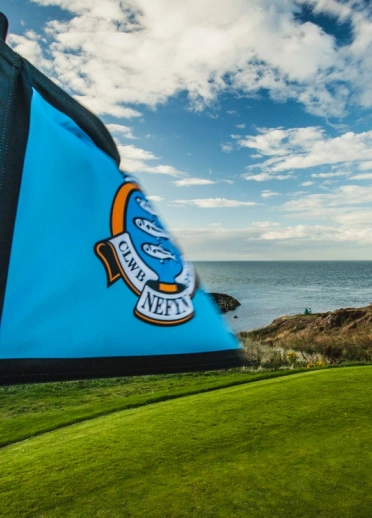 Baner las ar gwrs golff gyda 'Clwb Nefyn' wedi'i ysgrifennu arno