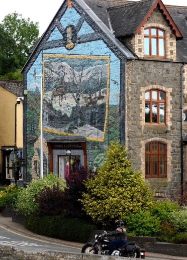 Tŷ gyda murlun wedi’i baentio ar ei ochr.