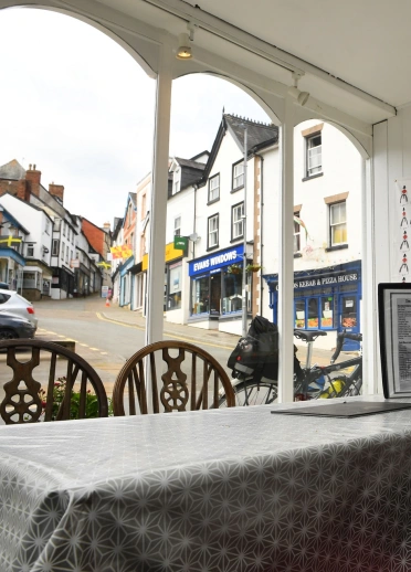 Yr olygfa o ffenest caffi, yn edrych ar stryd serth yn mynd am i fyny.