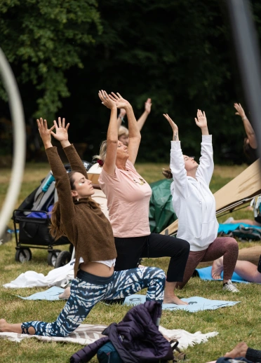 Tri o bobl yn gwneud ioga, yn penlinio ac yn ymestyn eu breichiau.