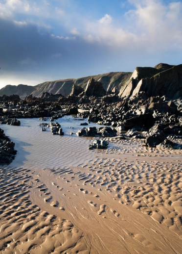 Y traeth a chreigiau ar y tywod
