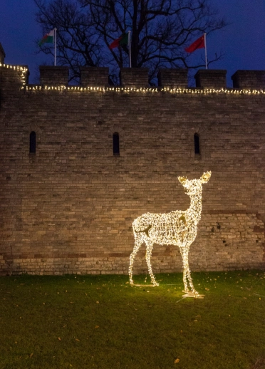 Addurn golau 3D mewn siâp carw Siôn Corn, wrth ymyl wal castell.
